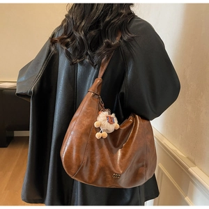 Detail of vintage brown leather tote bag showing soft texture and metal brand logo