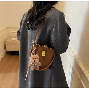 Détail d'un sac seau marron avec boucle dorée et pendentif chien en peluche doux