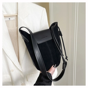 Macro detail of black frosted suede bucket bag with adjustable strap and embossed brand logo