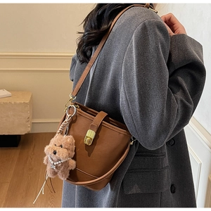 Vue détaillée du sac seau en cuir marron avec boucle dorée et breloque ours