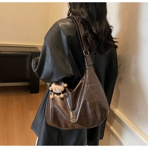 Detail of dark brown faux leather tote with plush bear charm and metallic logo print