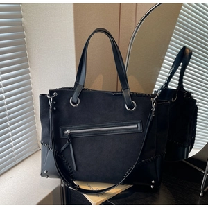 Detail view of black tote bag featuring mixed textures and decorative stitching accents