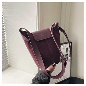 Detail of burgundy frosted suede bucket bag with leather texture and brand logo