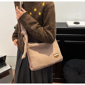 Detail of beige faux shearling crossbody bag with leather patch and knot shoulder strap