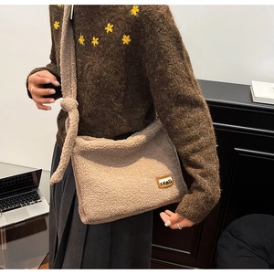 Detail of soft beige plush crossbody bag featuring a TXBD patch and knotted strap