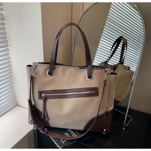 Detail view of khaki canvas tote with brown leather trim and retro woven stitching details