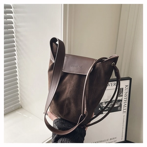 Detail of matte brown suede bucket bag featuring contrast leather trim and magnetic flap