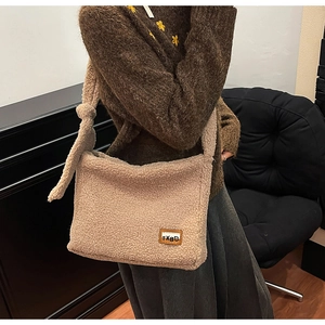 Detail of beige teddy faux fur tote bag with stylish knot shoulder strap and logo patch
