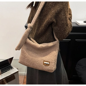 Detail of beige faux shearling crossbody bag showing soft texture and leather patch