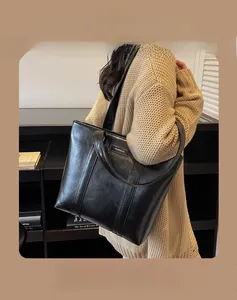 Détail du sac cabas élégant en cuir PU noir avec logo doré et texture lisse et raffinée