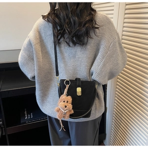 Détail du sac seau noir en cuir avec boucle dorée et breloque d'ours en peluche