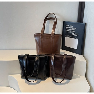 Détail de trois sacs cabas en similicuir brillant en marron, noir et couleur café foncé