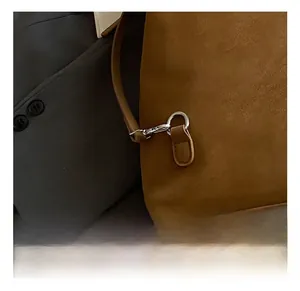 Détail du crochet métallique argenté et des coutures sur le sac à dos en cuir mat marron