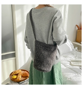 Détail du sac seau en peluche gris foncé dans une chambre au décor chaleureux