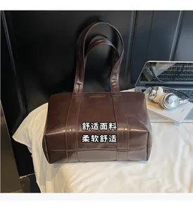 Détail d'un grand sac cabas marron foncé brillant avec une petite plaque métallique