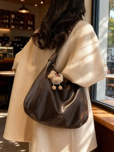 Brown soft faux leather hobo tote bag with a plush sheep charm in a cafe setting