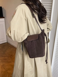 Dark brown frosted suede bucket bag with adjustable leather shoulder strap in use