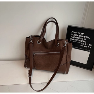 Detail of suede and smooth leather tote bag featuring contrast stitching and silver feet