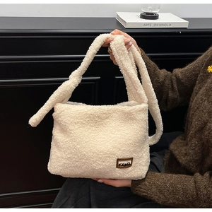 Detail of white faux shearling tote bag featuring a brown leather TXBD brand patch