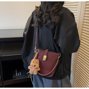 Détail du sac seau bordeaux vintage avec fermoir doré et breloque ours sur le mannequin