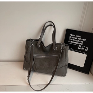 Detail of dark grey tote bag with suede leather textures, silver studs and metal zippers