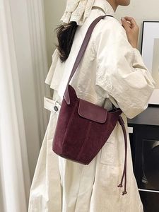 Frosted suede burgundy bucket bag with magnetic closure shown in a lifestyle model shot