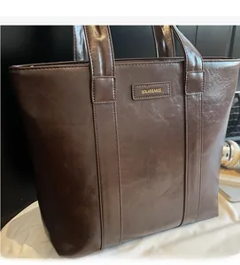 Détail du sac cabas marron foncé brillant avec texture en cuir et logo de marque