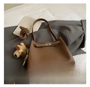 Detail of brown litchi pattern leather handbag with metal buckle and dog charm