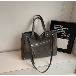 Detail of grey tote bag featuring braided side accents and smooth leather stitching