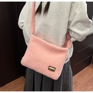 Close-up of pink fuzzy crossbody bag with a plush sherpa texture and brand logo patch