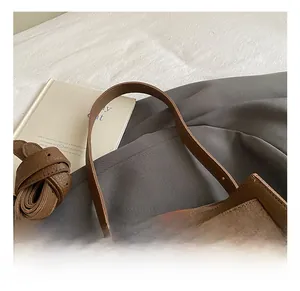 Detailed macro view of the brown lychee grain leather finish and metal clasp on the handbag