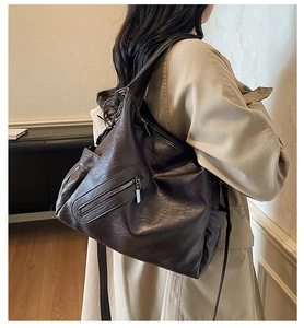 Detail of dark brown leather tote bag showing soft litchi texture and side metal zipper