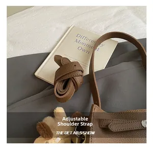 Detail of adjustable leather shoulder strap with metal buckle and plush dog charm