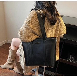 Détail d'un grand sac cabas noir en similicuir avec plaque métallique sur un mannequin
