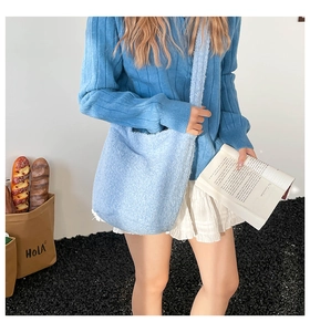 Détail d'un sac cabas en peluche bleu clair porté avec une tenue en maille douce