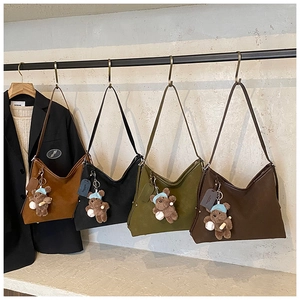 Detail of four matte tote bags in earth tones with rivet accents and plush bear charms