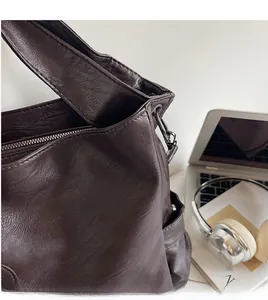 Detailed view of dark brown leather tote bag with soft lychee texture and silver zipper