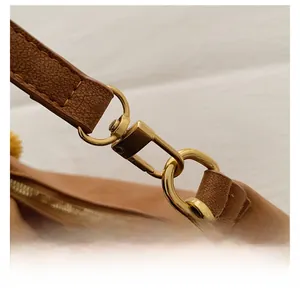 Detail of the golden detachable metal hook and brown lychee grain texture on a PU bag