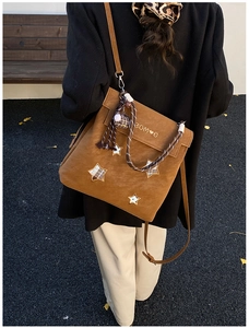 Détail du sac à dos givré caramel avec écussons étoiles et poignée décorative tissée
