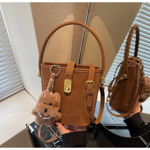 Détail d'un sac seau vintage marron avec charm chiot en peluche et boucles dorées