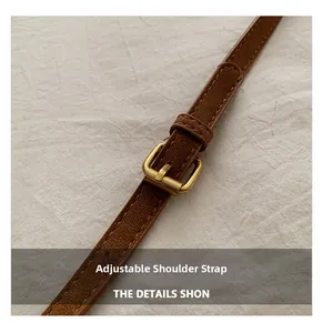 Close-up of adjustable brown litchi pattern leather shoulder strap with gold buckle