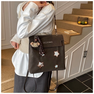 Détail du sac à dos mat marron foncé avec écussons étoiles et breloque ours mignon