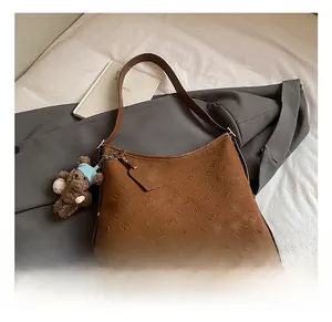 Detail of caramel brown embossed tote bag with teddy charm on textured background