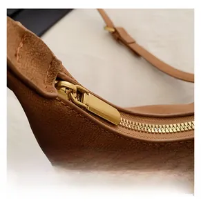 Close-up of smooth gold-tone zipper on brown lychee texture leather handbag detail