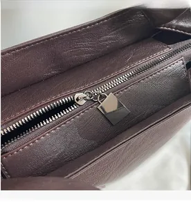 Close-up of smooth metal zipper and textured dark brown leather on tote bag