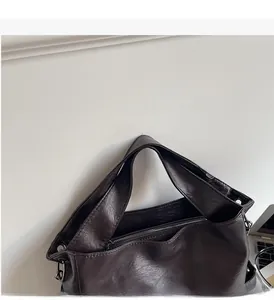 Detailed view of dark brown tote bag showing leather texture and wide shoulder strap