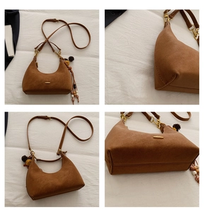 Detail of matte brown hobo bag featuring ethnic tassel charm and golden metal hardware