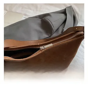 Close-up of a dark brown embossed leather tote with a silver metal zipper and branded tag