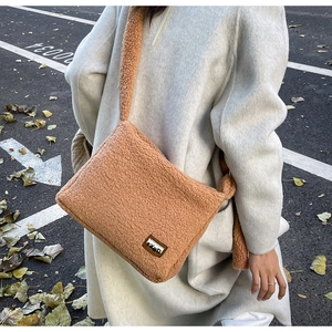 Detailed close-up of brown faux fur crossbody bag with leather logo tag and teddy texture