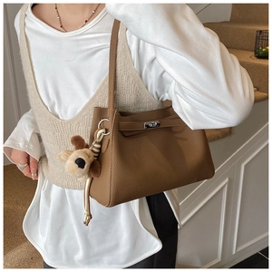 Detail of a brown lychee pattern leather bucket bag with metal turn-lock and puppy charm